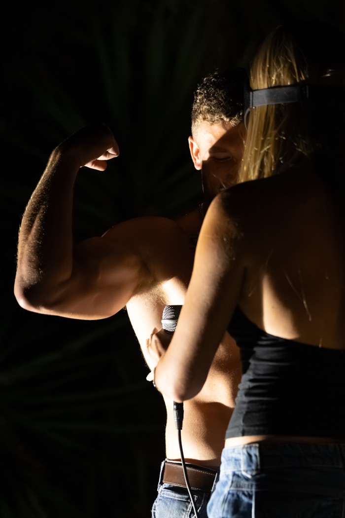 Cameron flexing his biceps while Eris feels his arm during round two