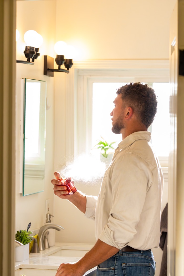 Cameron applying cologne in the bathroom before the show